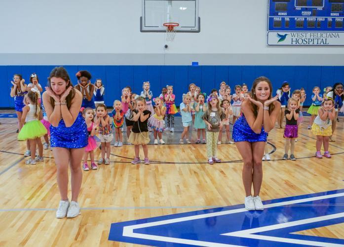 West Feliciana High Fleur de Lis dance members Ella McKinney and Madzy Leak  practice a dance move with PreK and kindergarteners at the Glam Mini Dance Camp on Sunday. 